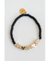 Black beaded bracelet with gold pave heart-shaped charms on a light grey background