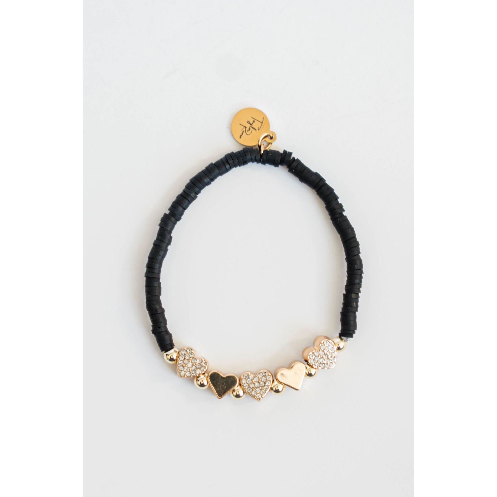 Black beaded bracelet with gold pave heart-shaped charms on a light grey background