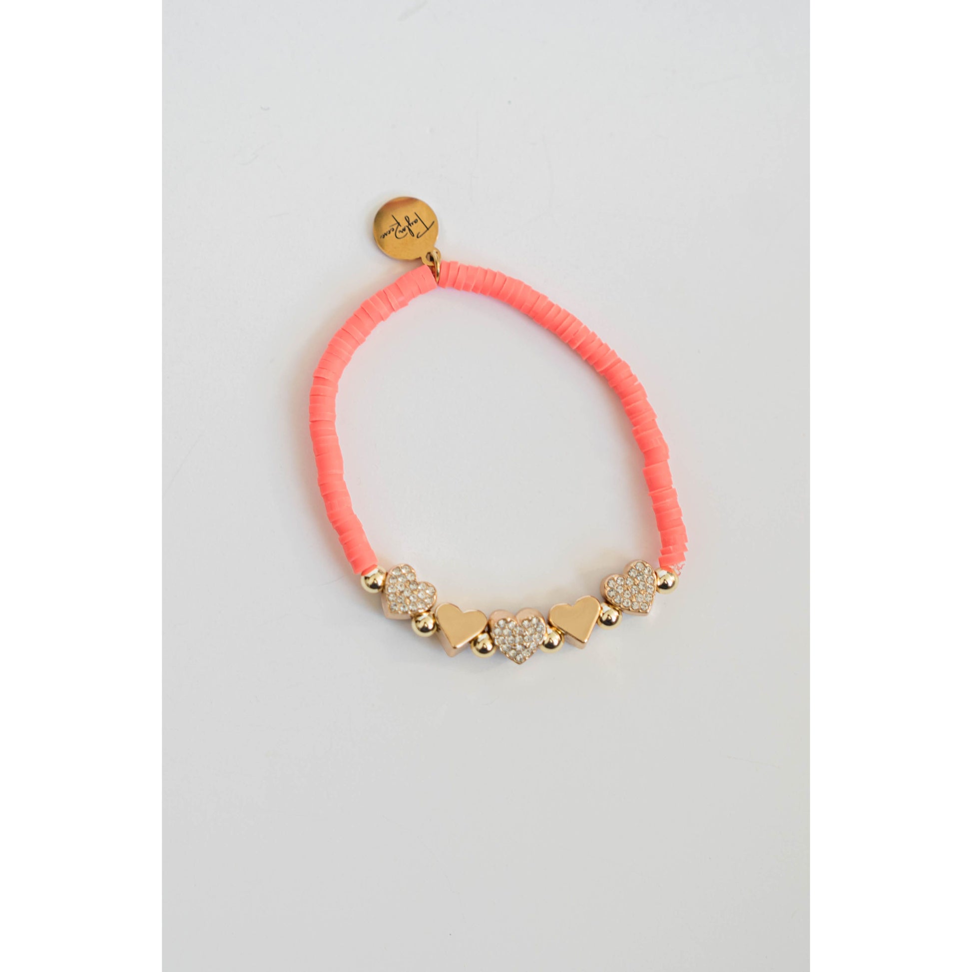 coral pink beaded bracelet with gold pave heart shaped beads on a light gray background