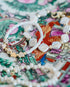 two bracelets with white beads and pearls and gold accents on a multicolor vintage plate