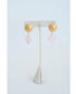 earrings with large gold textured circular posts and light pink quartz heart dangle accents on an earring stand on a light background