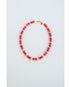 Necklace with red beads, gold spacers, white pearl heart charms and a gold pave clasp on a light gray background