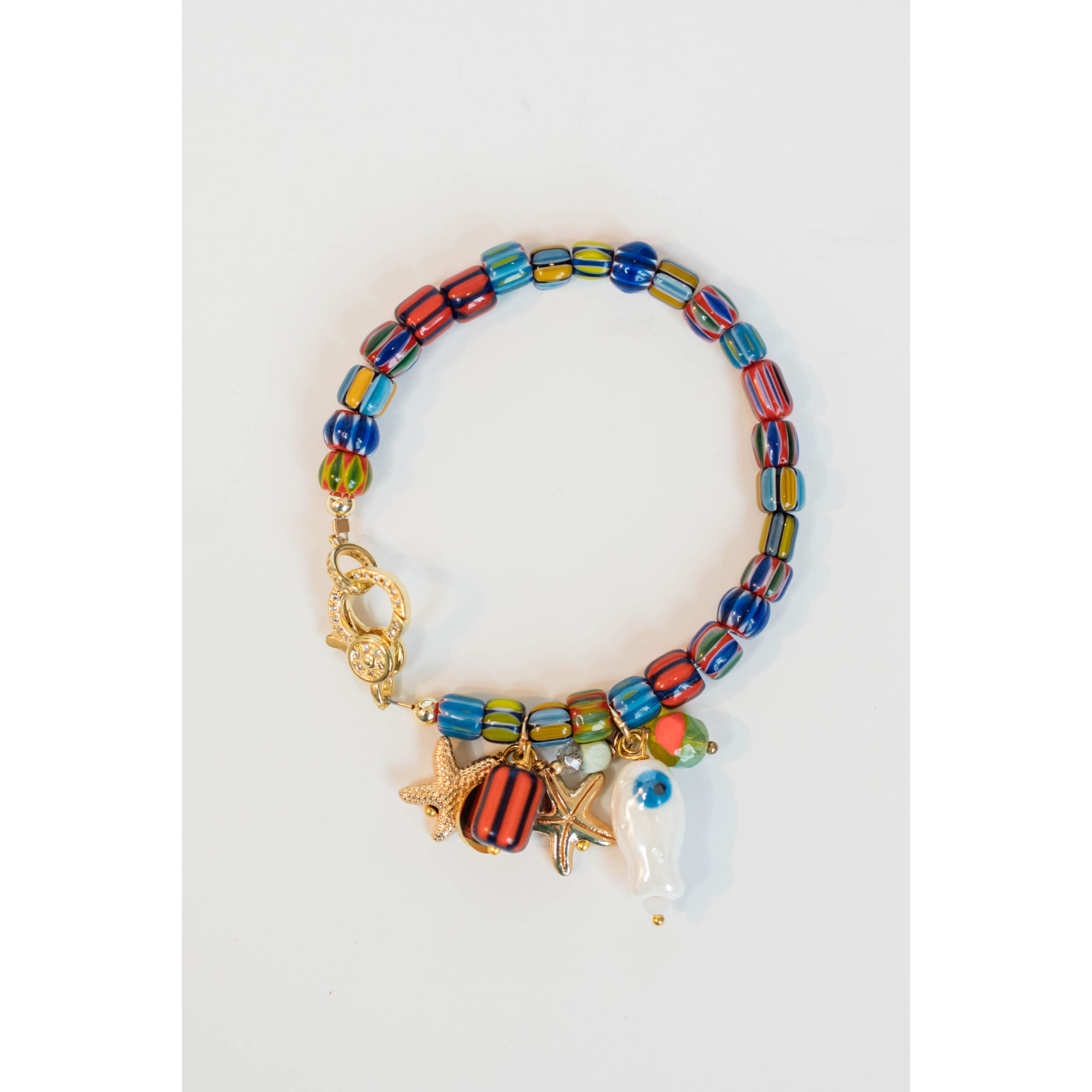 colorful beaded bracelet with charms of starfish and fish charm with a gold pave lever clasp on a light grey background