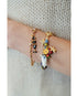 Multicolored bracelets with starfish and fish charms on a wrist against a neutral background