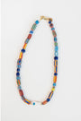 colorful painted stripe beaded necklace with a white fish charm on a light grey background