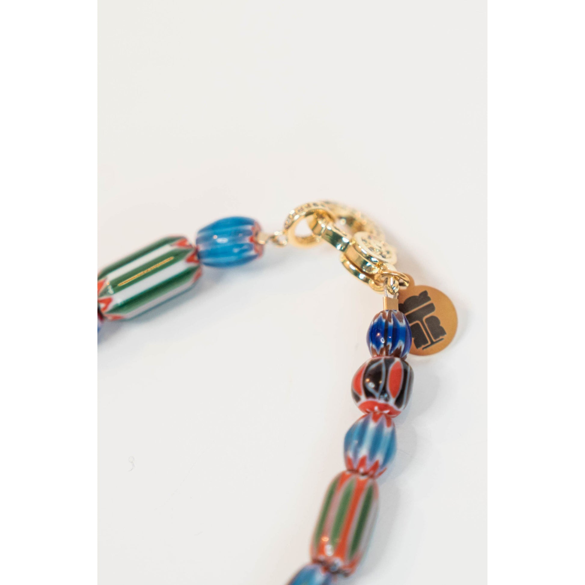 Closeup picture of a colorful striped beaded necklace with a gold clasp on a white background