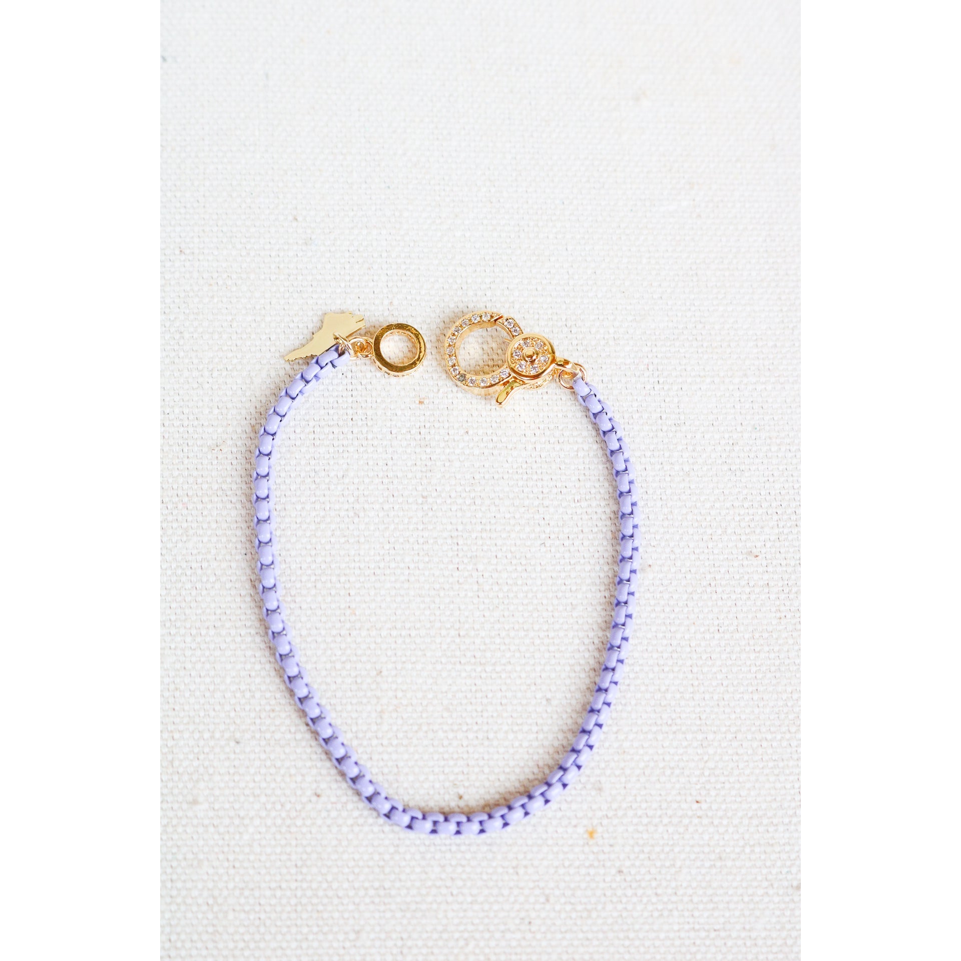 lavender box chain bracelet with a gold pave lever clasp on a light grey background
