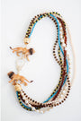 statement necklace with multiple strands of multicolored beads  and lion figurines with a gold pave clasp on a white background