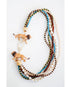 statement necklace with multiple strands of multicolored beads  and lion figurines with a gold pave clasp on a white background