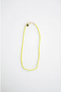 neon yellow and green color block cord necklace with a gold carabiner clasp on a light background