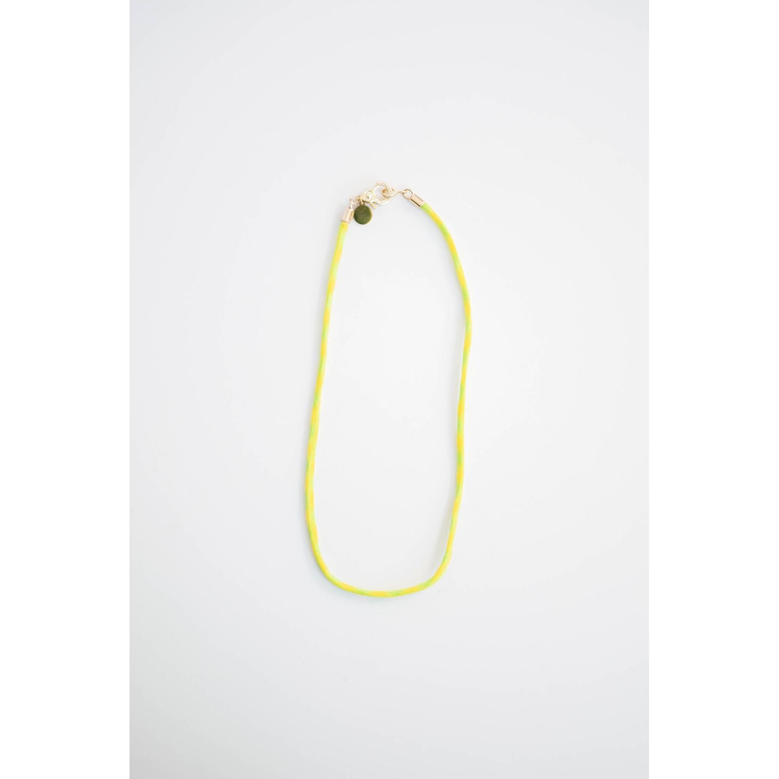 neon yellow and green color block cord necklace with a gold carabiner clasp on a light background