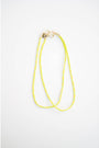 two neon yellow and green color block cord necklaces with a gold carabiner clasp on a light background