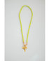 Neon yellow and green cord necklace with a gold shark tooth pendant on a light gray background
