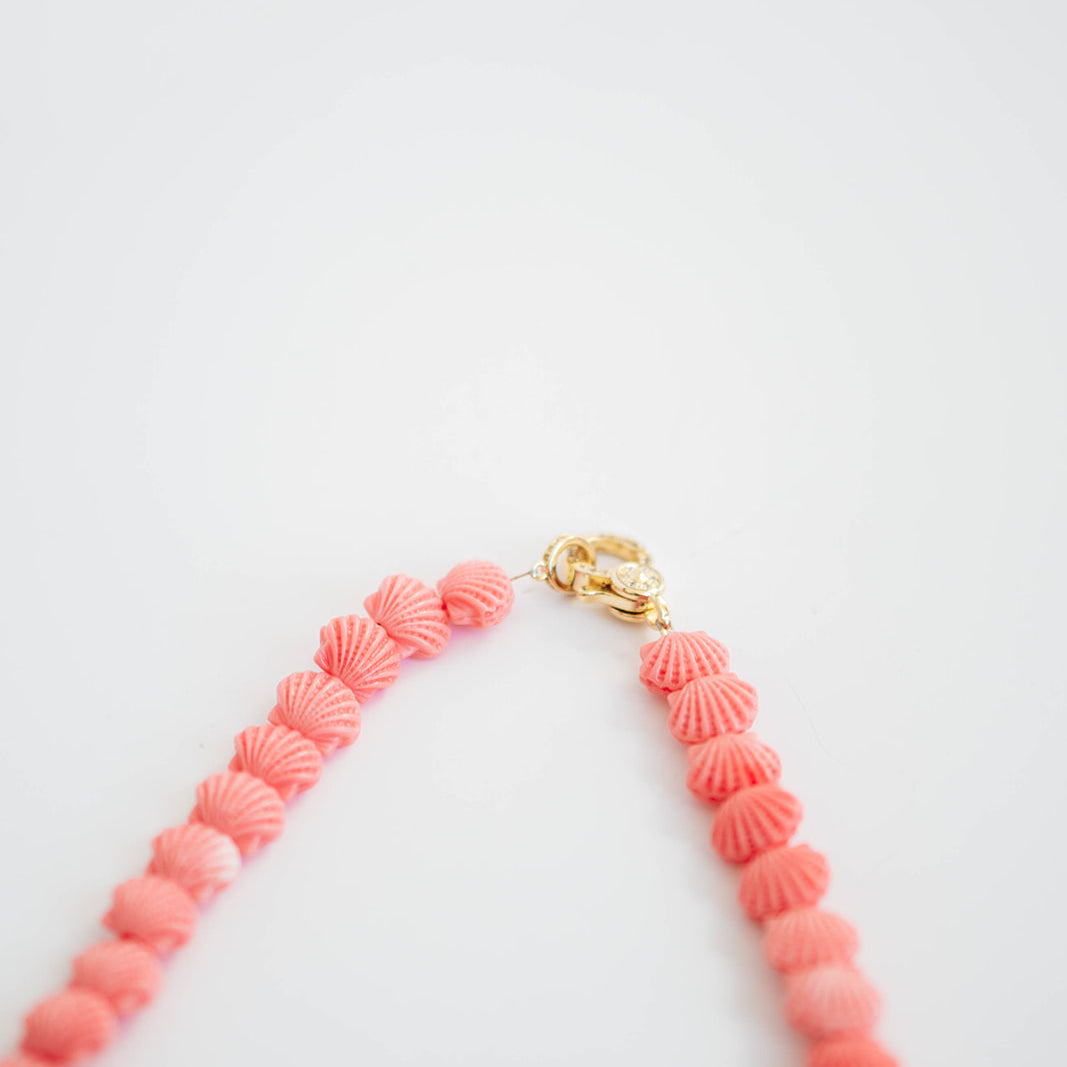 Necklace with pink beads and gold clasp on a white background