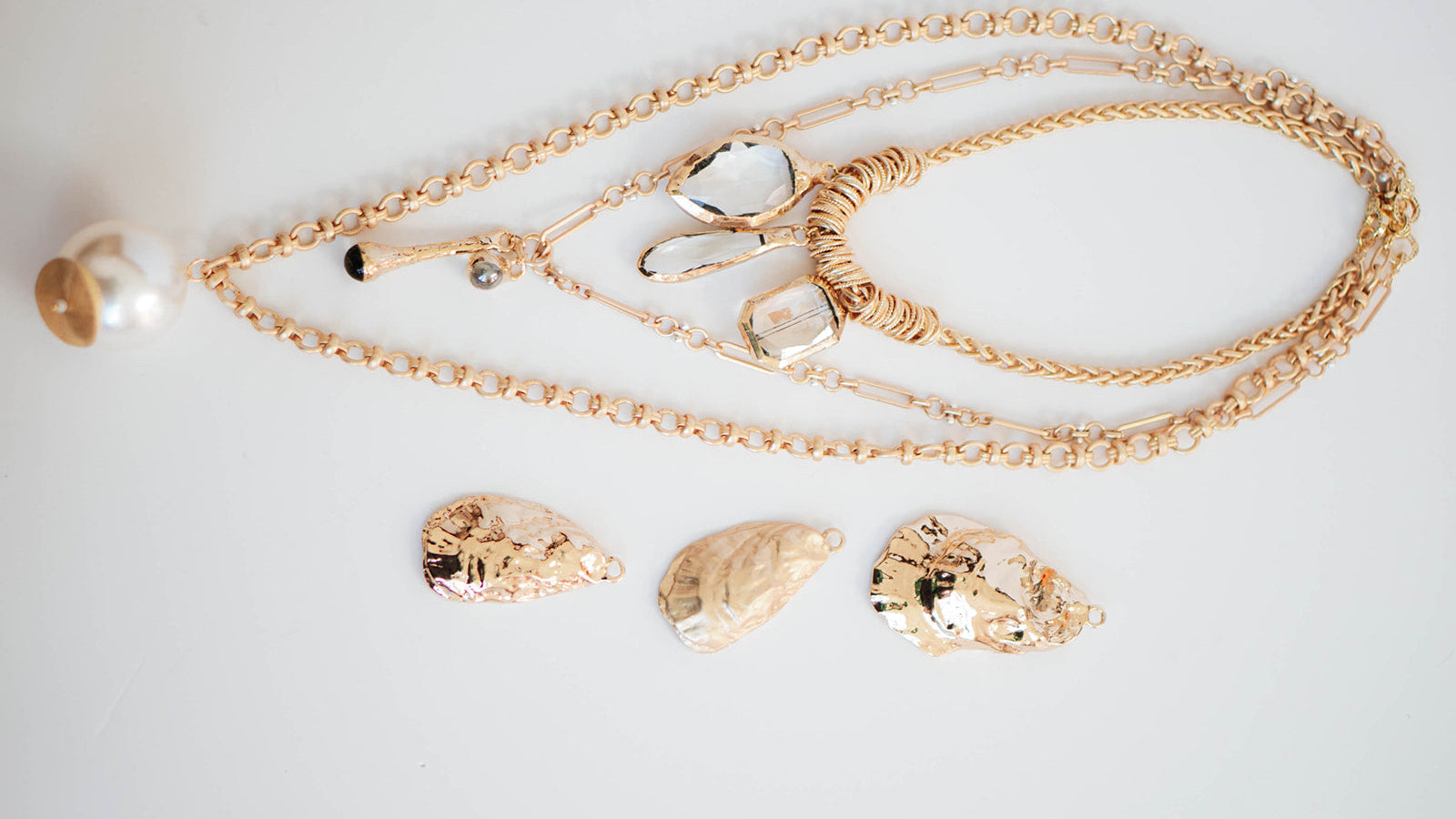 Gold necklace with shell pendants on a light gray background