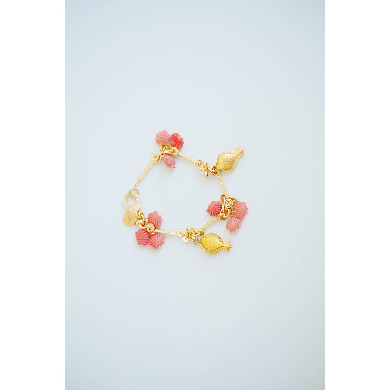 Gold and pink charm bracelet on a light blue background