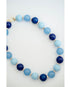 A beaded necklace made of alternating light blue and dark navy blue round beads, separated by small gold spacer beads, photographed on a clean white background.