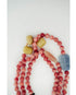 A beaded necklace with round pinkish-red beads, a light blue stone bead, and three textured yellow-green accent beads, arranged on a plain white background.