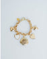 Gold bracelet with heart and round charm on a light gray background