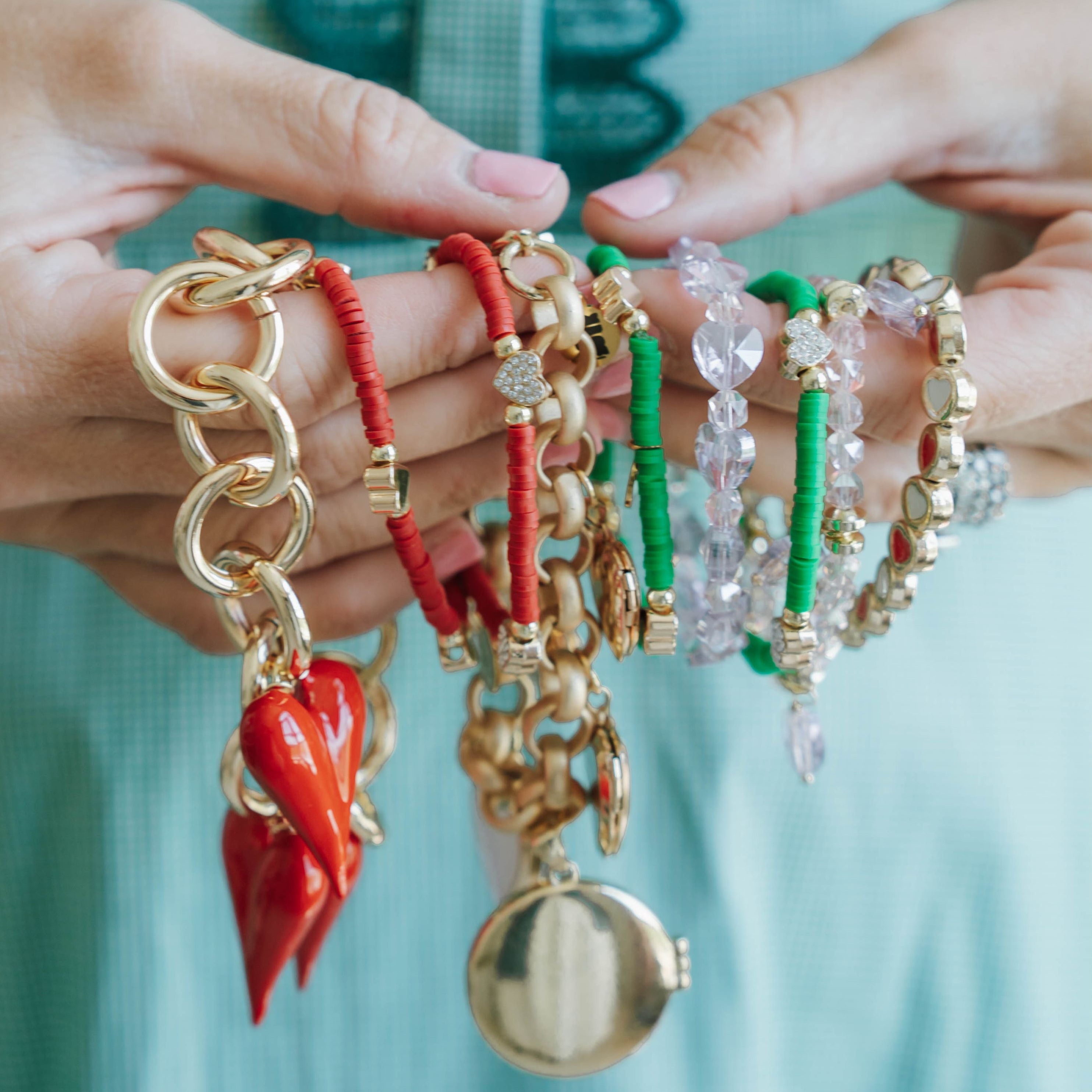 Hands holding a collection of colorful bracelets with various designs.