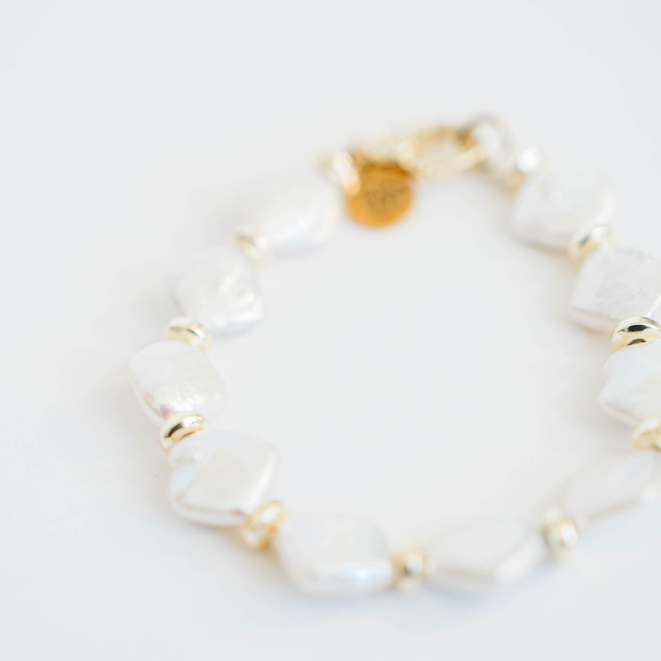 Pearl bracelet with gold accents on a light gray background