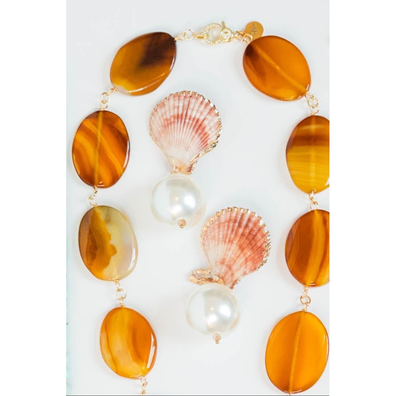 Necklace with amber-colored beads, pearls, and seashells on a white background
