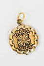 gold and brass charm with "good luck" engraved and a 4 leaf clover in the center on a light background