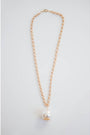 thick gold chain necklace with an oversized pearl pendant on a light grey background