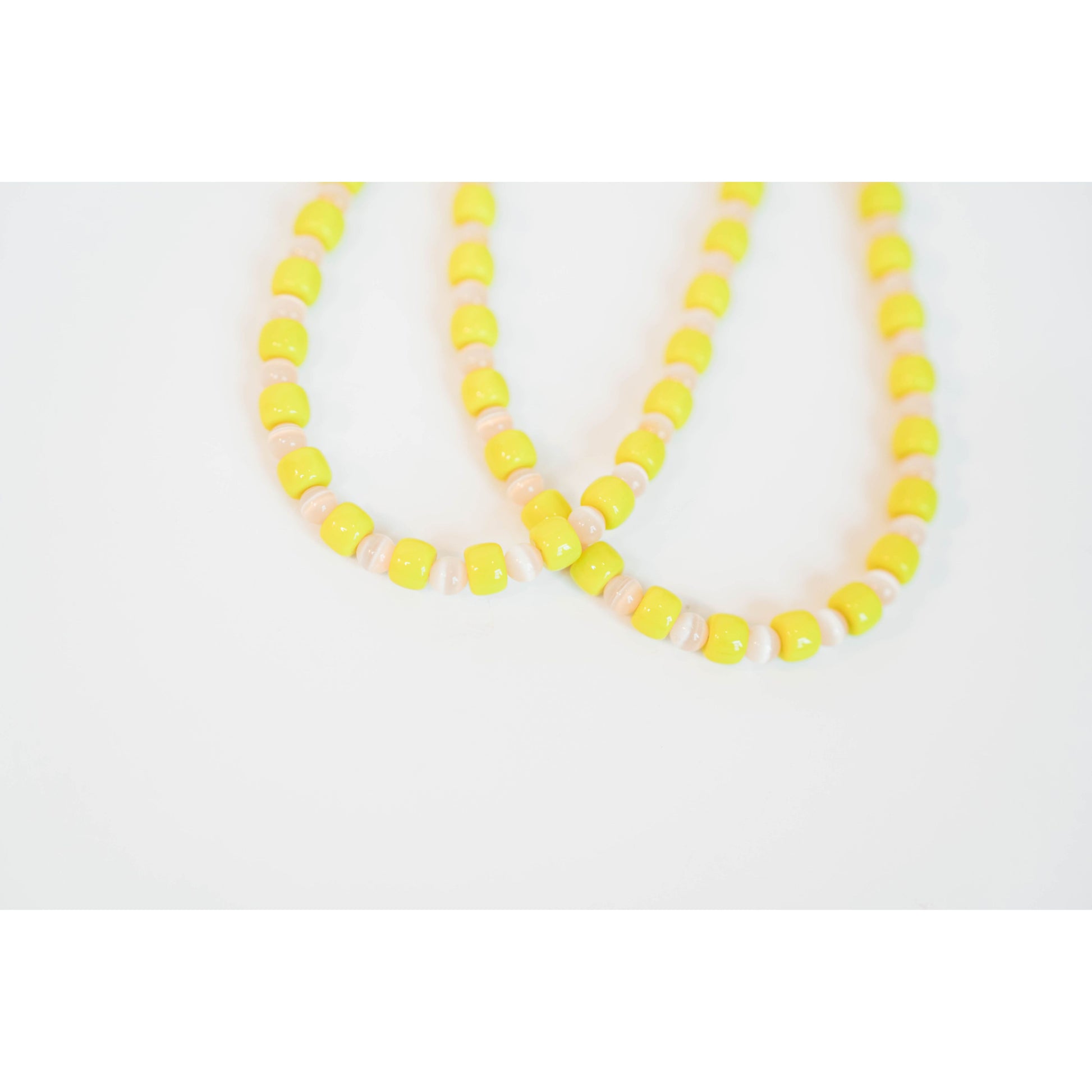 two neon yellow beaded necklaces with glass roller beads in between and a gold pave clasp