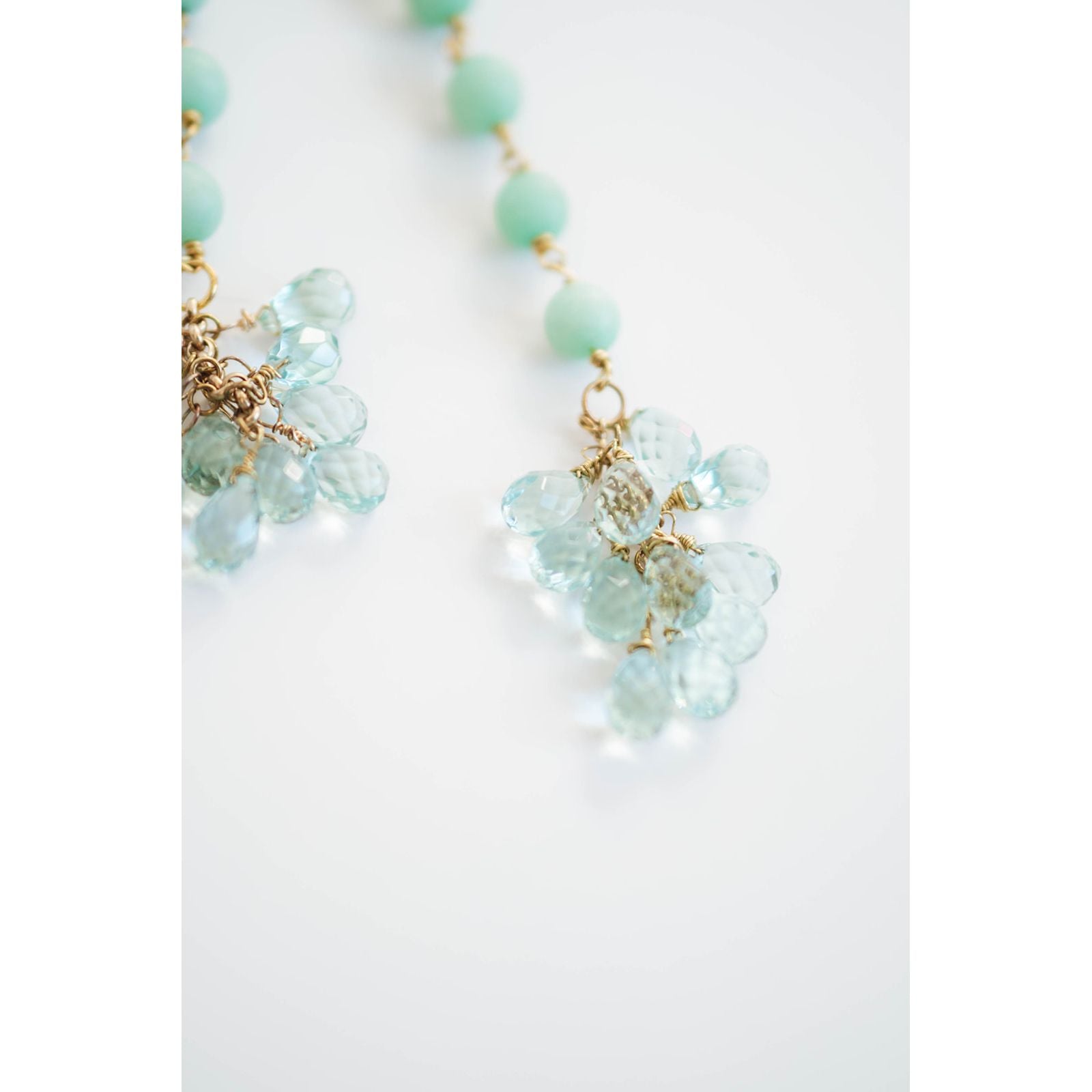 Necklace with light blue beads and gold accents on a white background