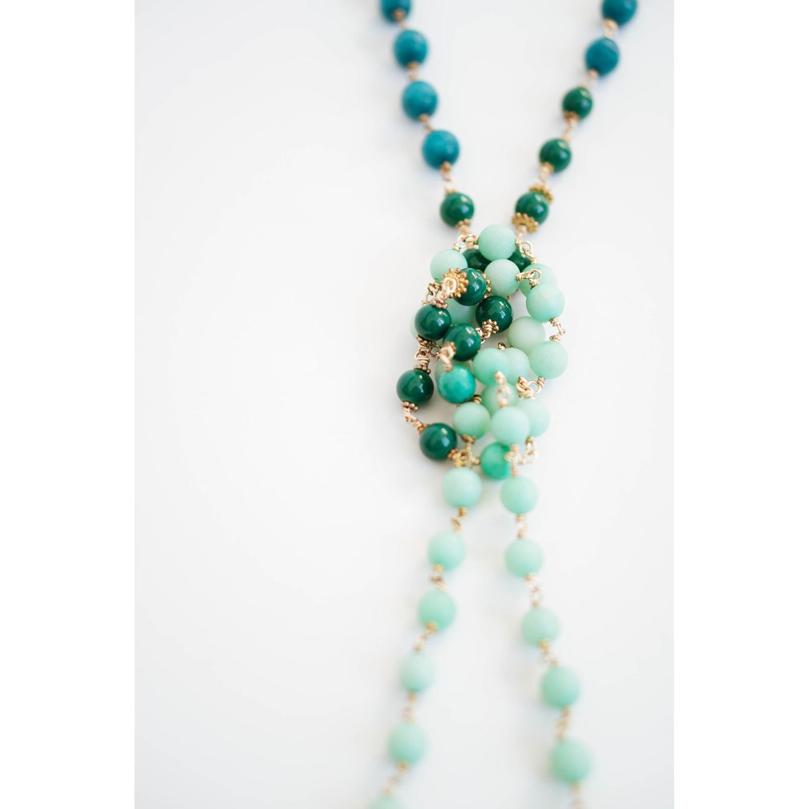 Necklace with green and gold beads on a white background