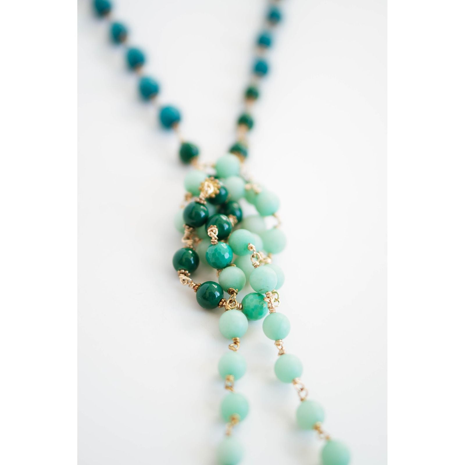 Necklace with green and gold beads on a white background