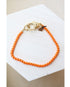 orange colored box chain bracelet with a gold pave lever clasp on a light background