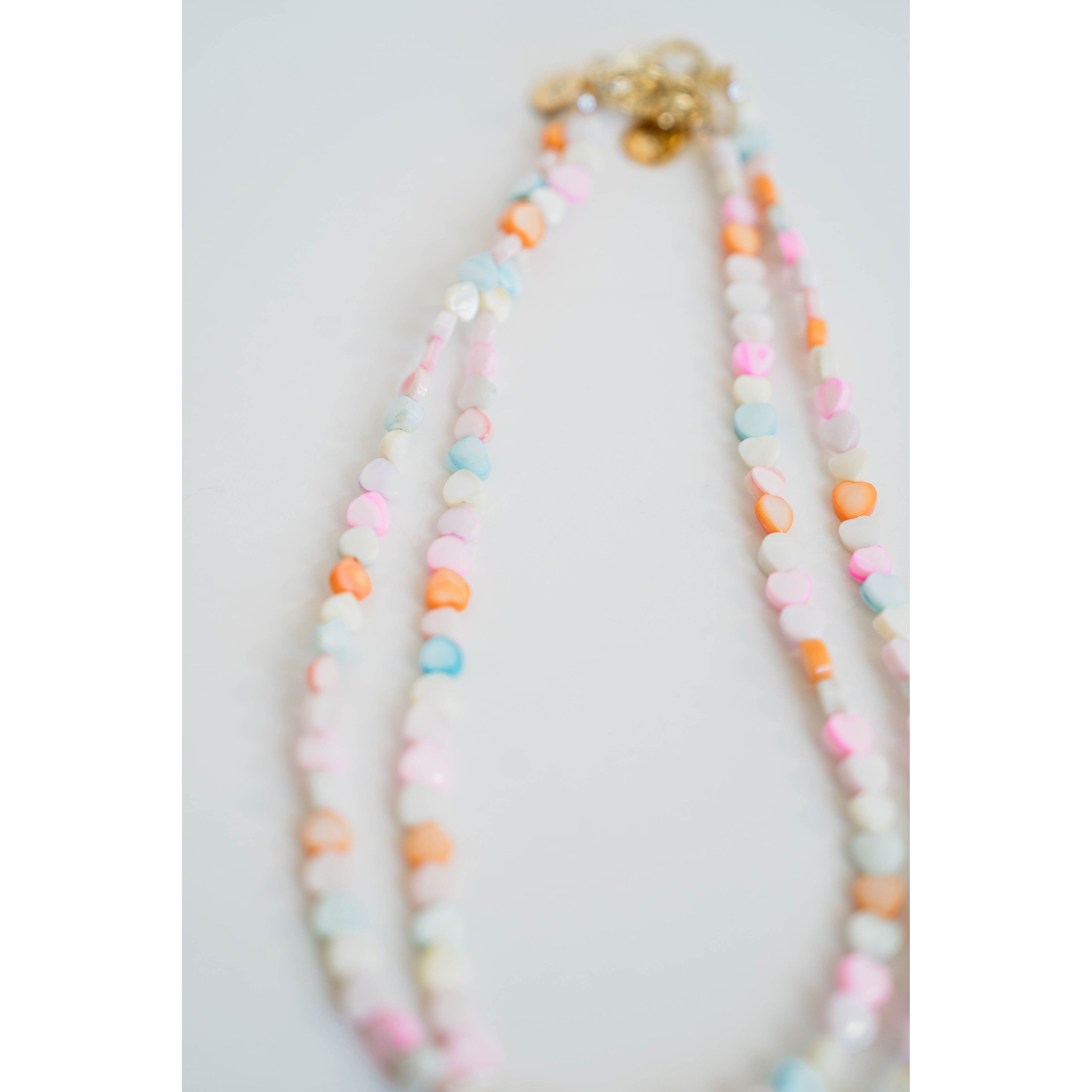 two colorful necklaces of pastel colored heart beads with gold clasps