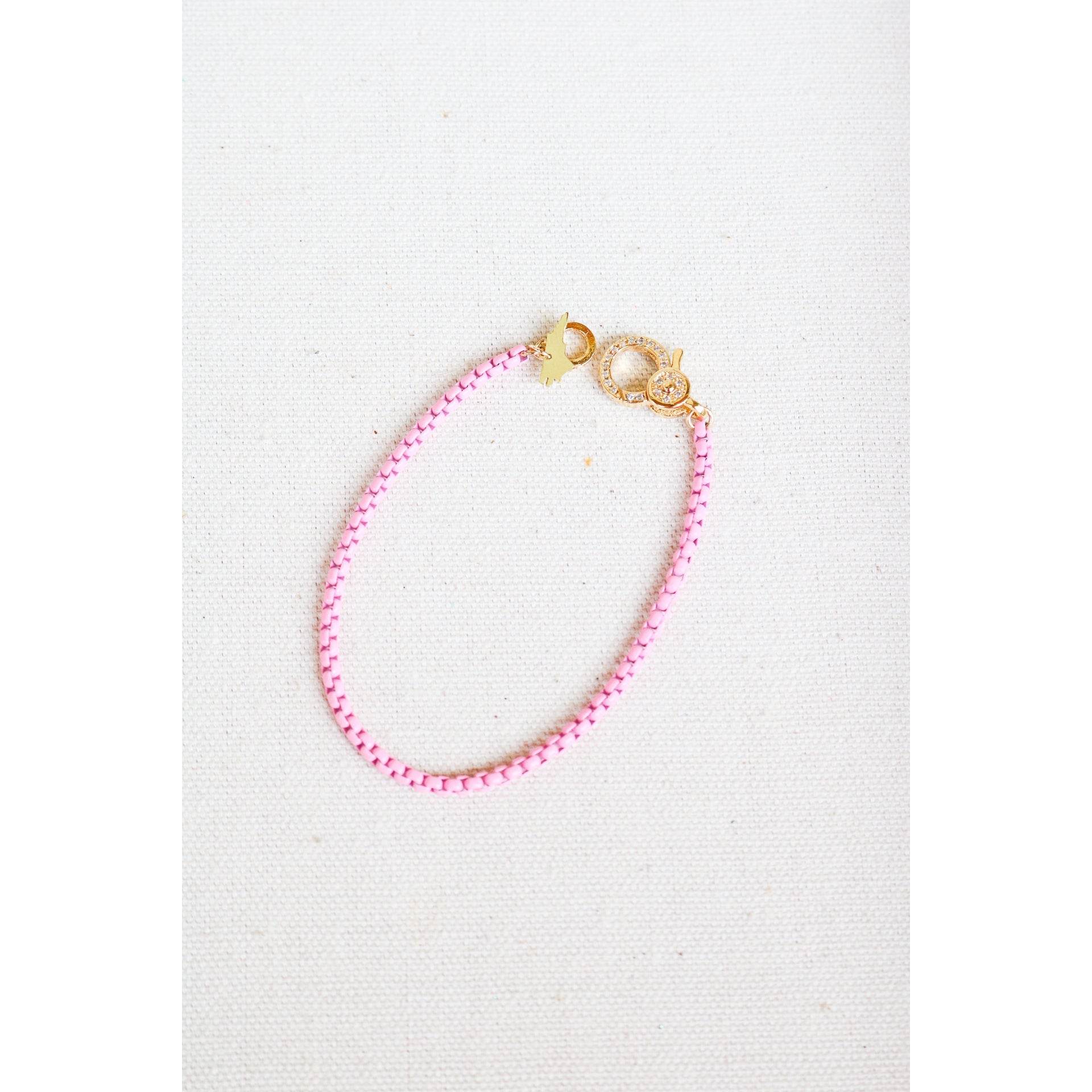 light pink box chain bracelet with a gold pave lever clasp on a light grey background