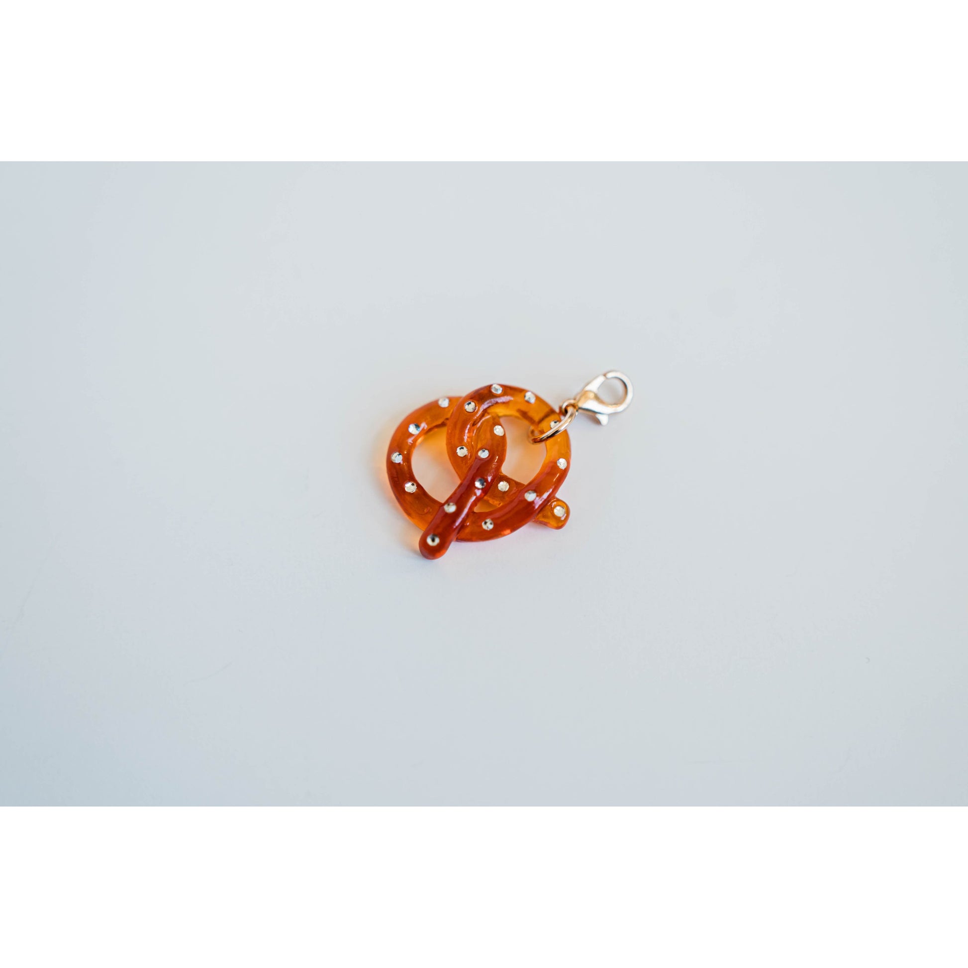 light brown acrylic pretzel charm with rhinestone detailing on a light grey background