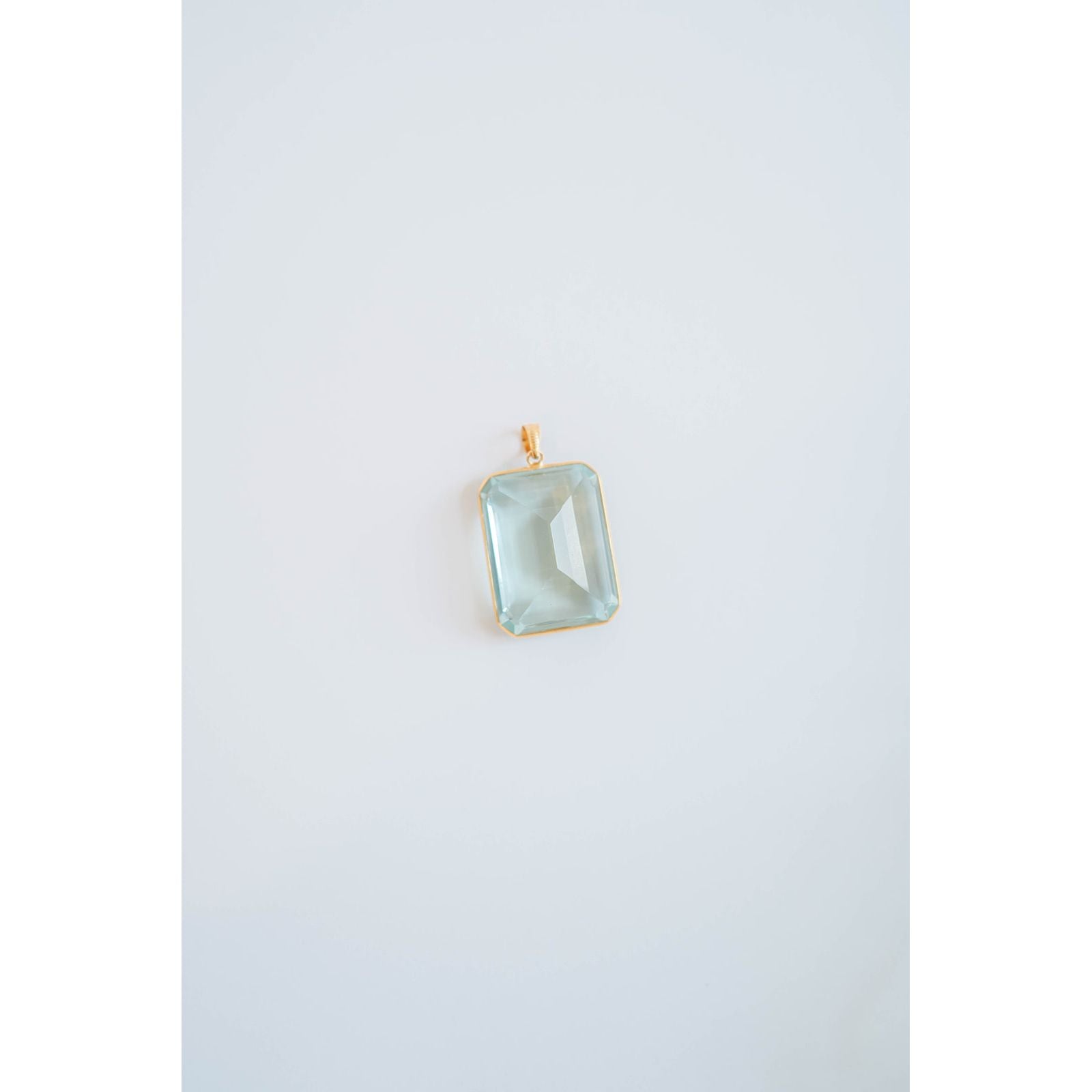 Rectangular light blue gemstone pendant in a gold frame on a white background