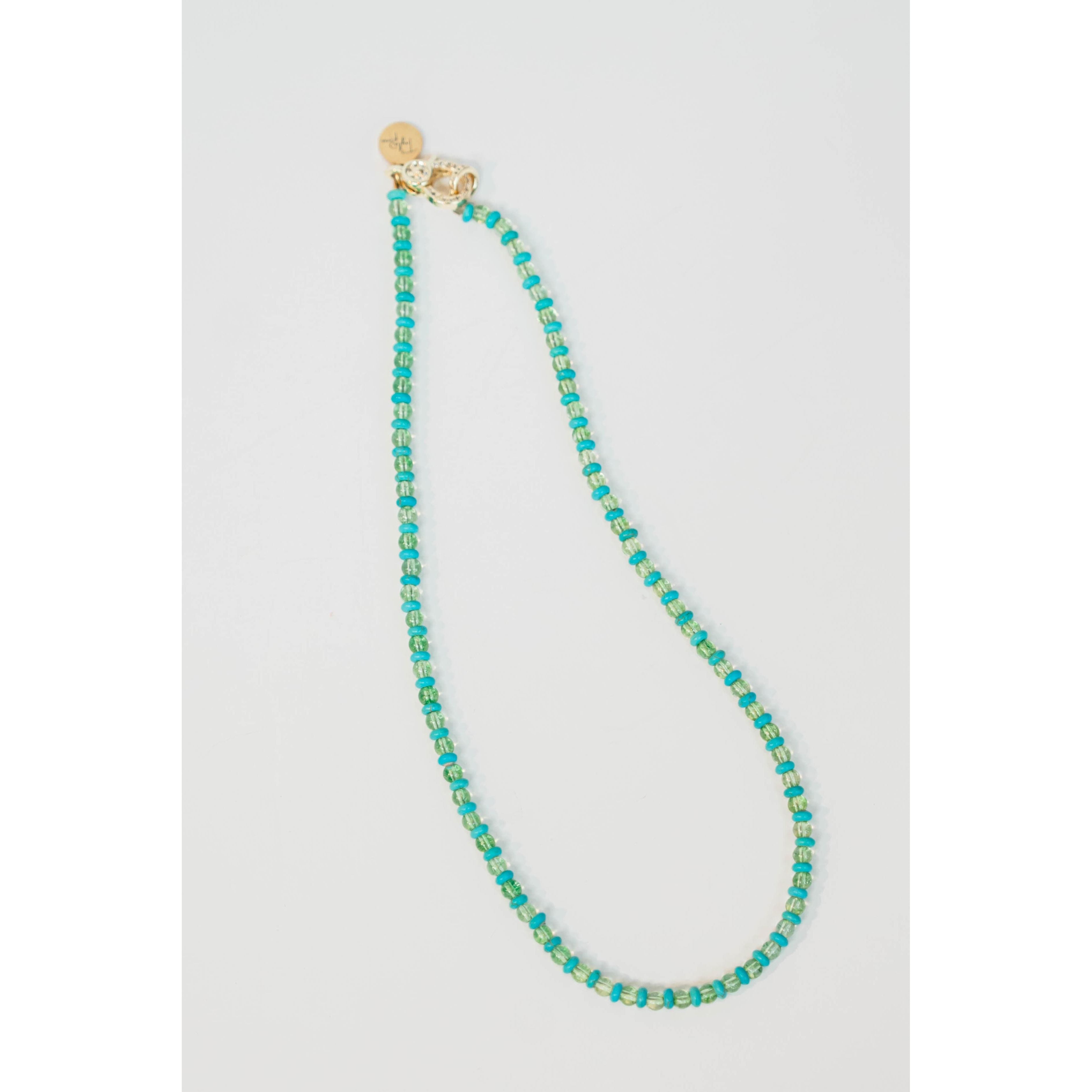 Turquoise beaded necklace with a gold pave lever clasp on a light gray background