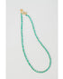 Turquoise beaded necklace with a gold pave lever clasp on a light gray background