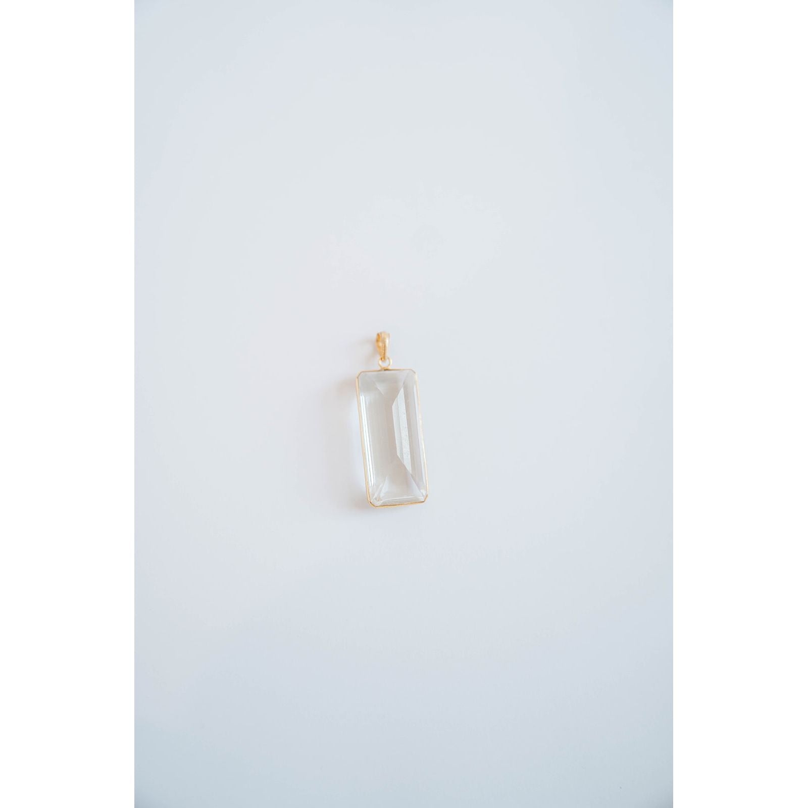 rectangular crystal pendant in a gold frame against a light grey background