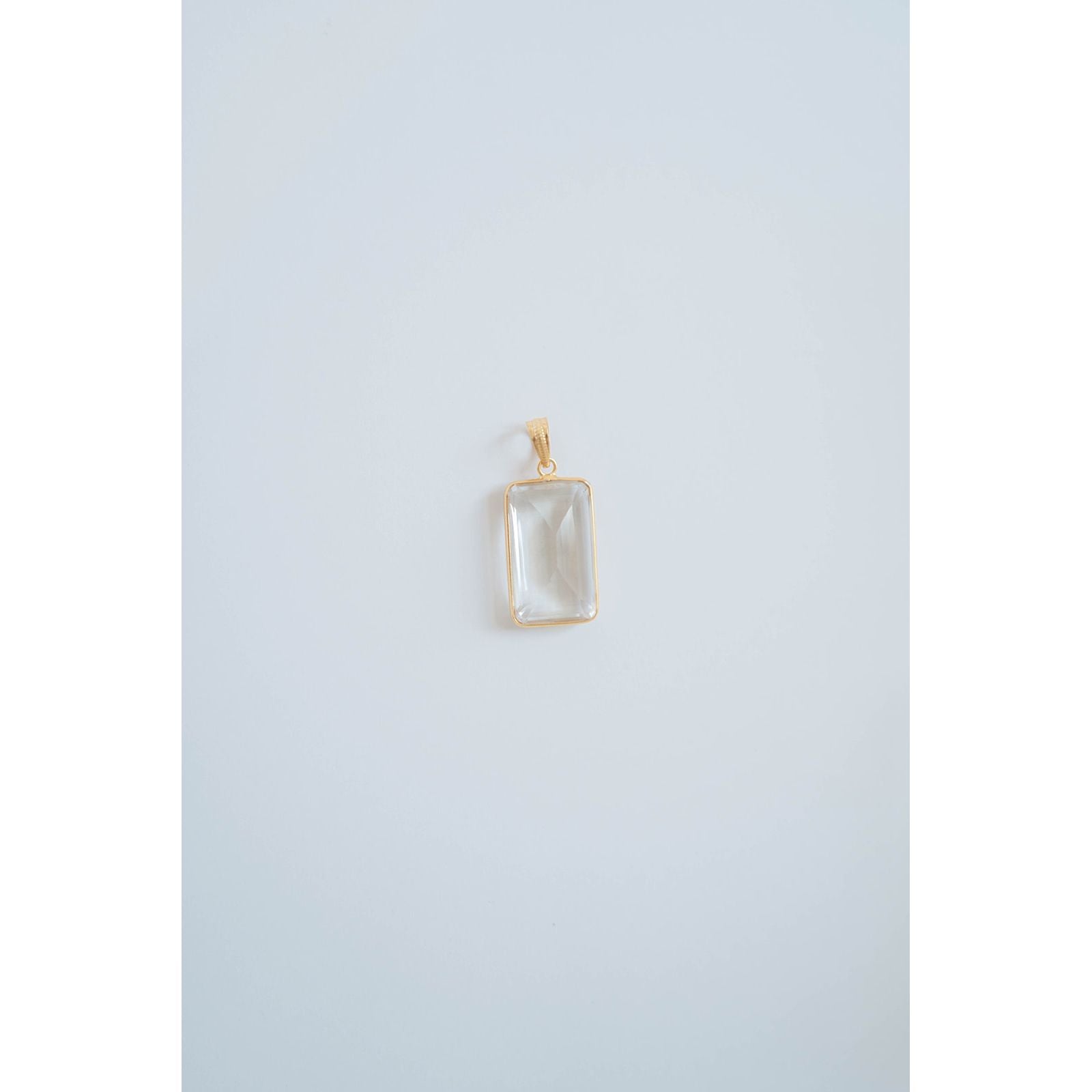 rectangular crystal pendant in a gold frame against a light grey background