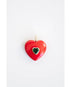 Red heart-shaped pendant with a green crystal center gemstone on a light background