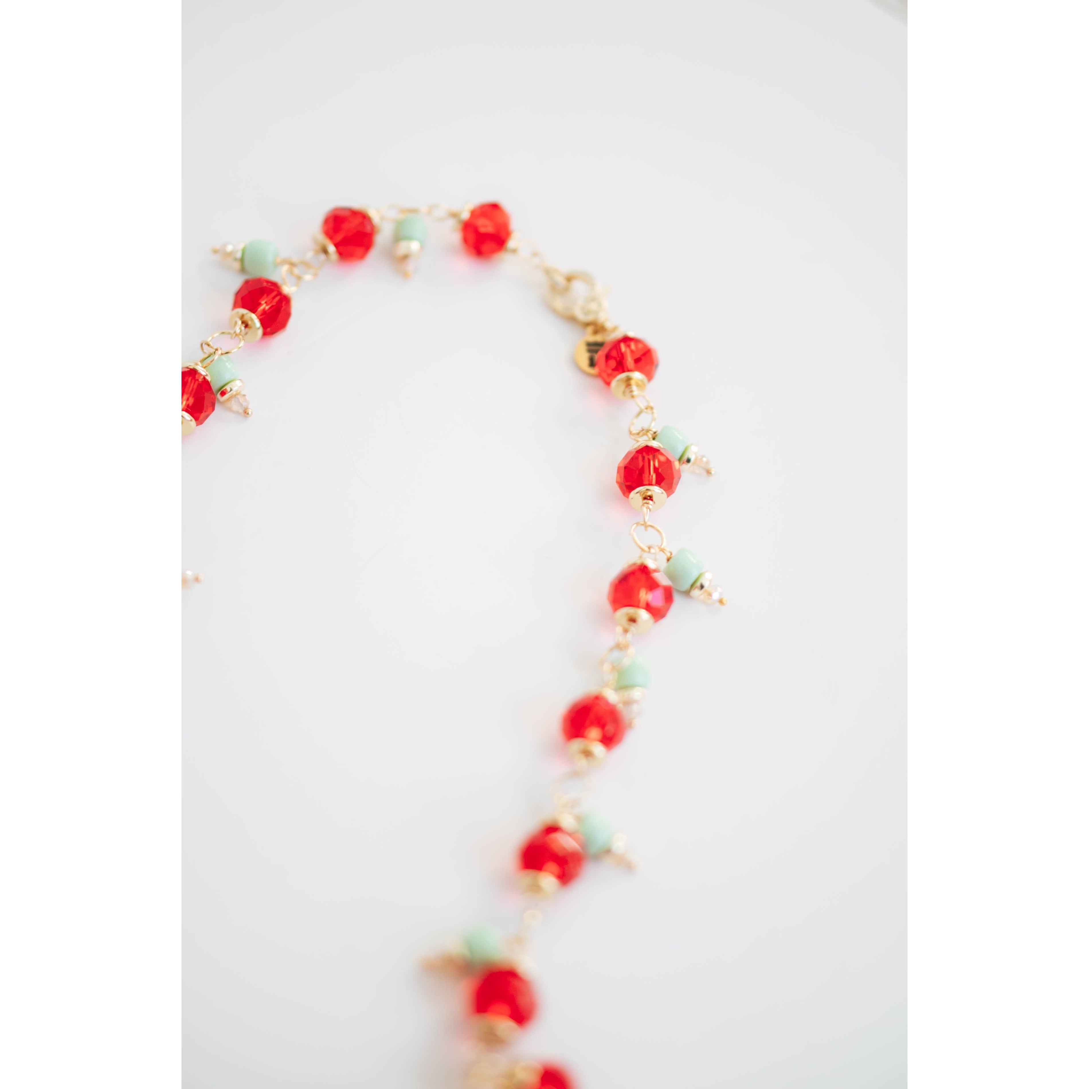Necklace with red crystal and mint green beads on a white background