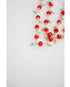 Necklace with red crystal and mint green and gold beads on a white background