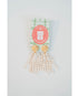 Gold and pearl tassel earrings on a white background with a visible brand label.