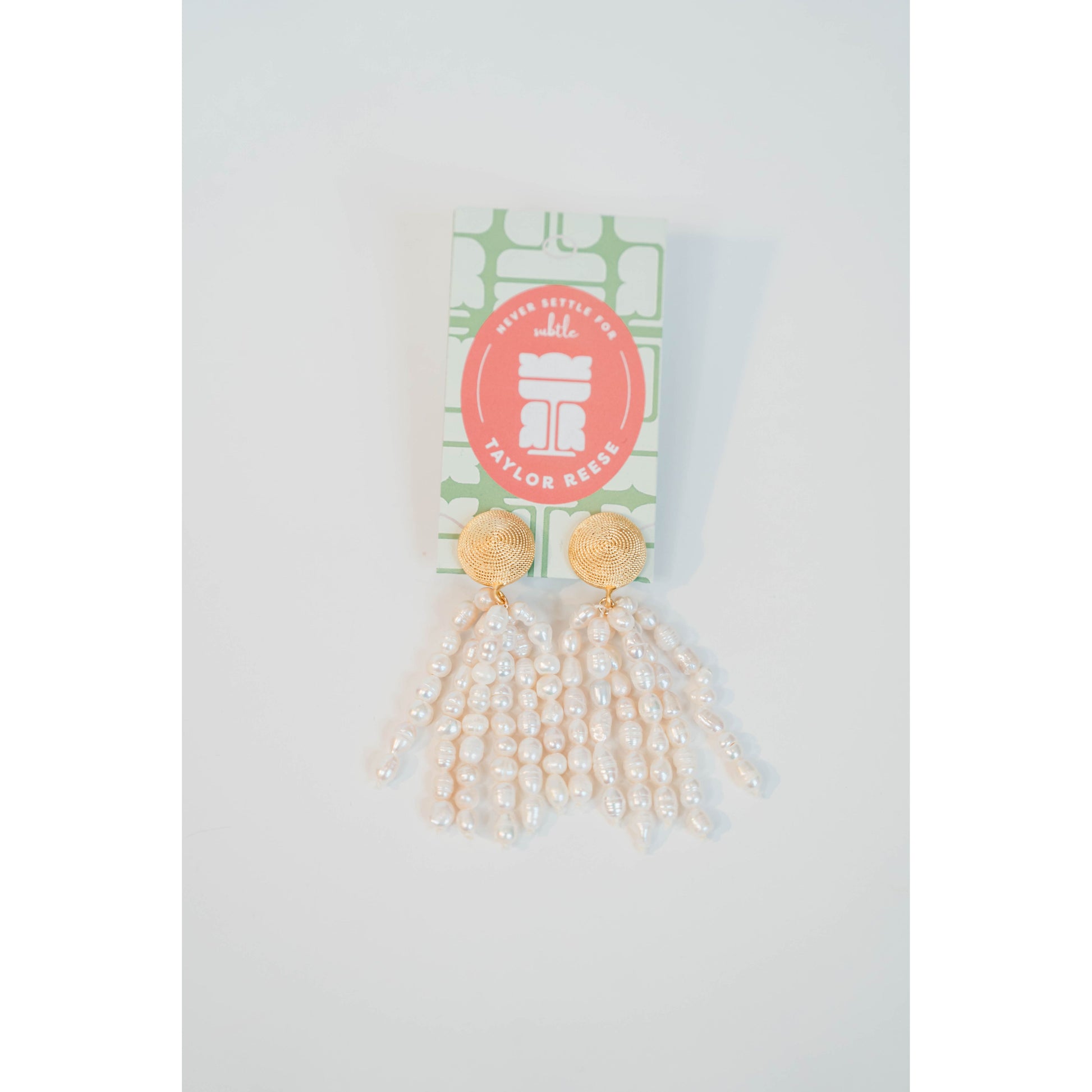 Gold and pearl tassel earrings on a white background with a visible brand label.