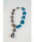 statement necklace with gold chain and blue and grey stone accents on a light grey background