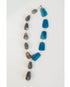 statement necklace with gold chain and blue and grey stone accents on a light grey background