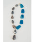statement necklace with gold chain and blue and grey stone accents on a light grey background