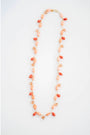 Necklace with orange and peach seashell beads on a white background